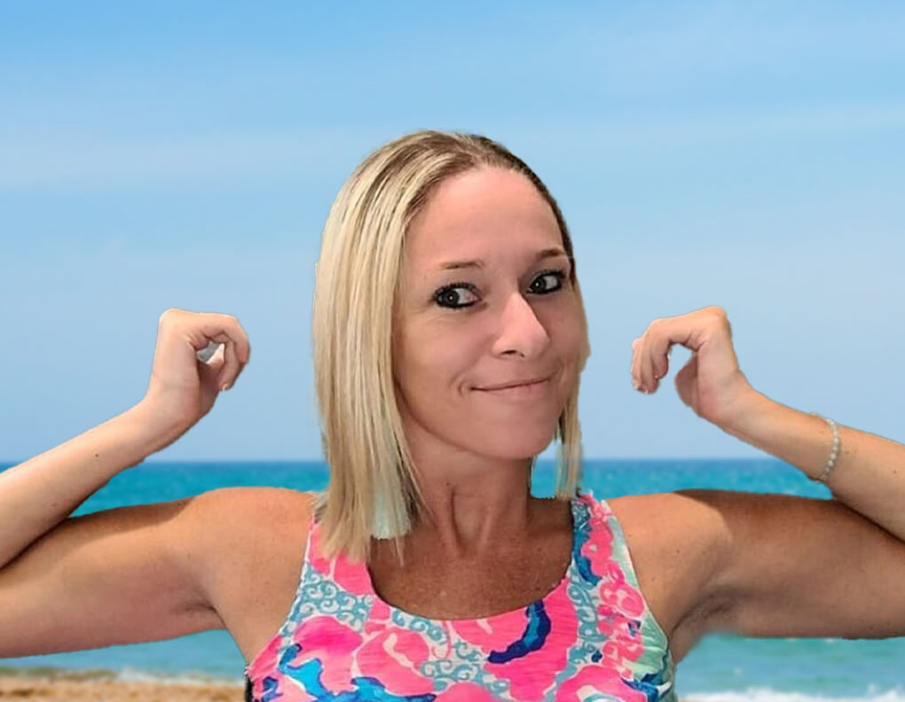 Ali at the beach in a colorful swimsuit in a victory pose in bright pink tank top